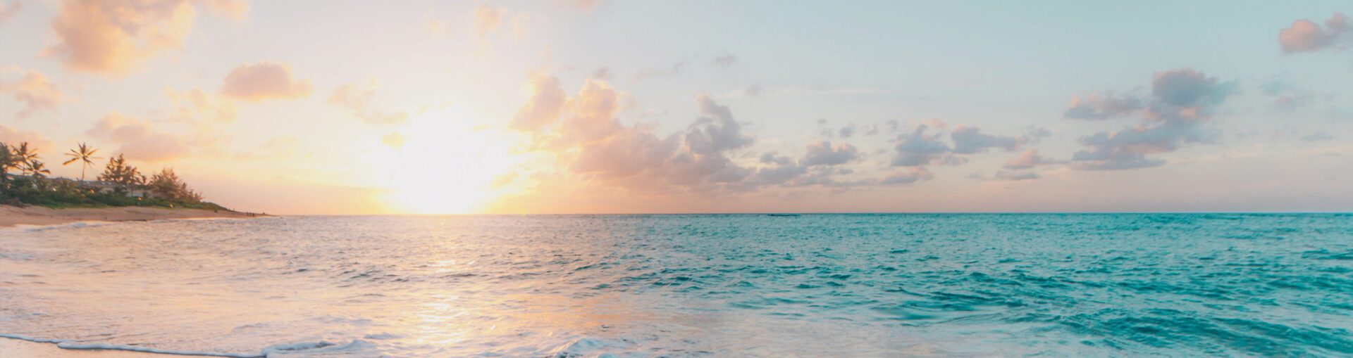 A view of the ocean at sunset with clouds in the sky.